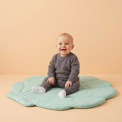 Kis baba ül a játszószőnyegen és nevet