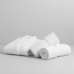 Összehajtott szállodai köntös és összecsavart törölközők